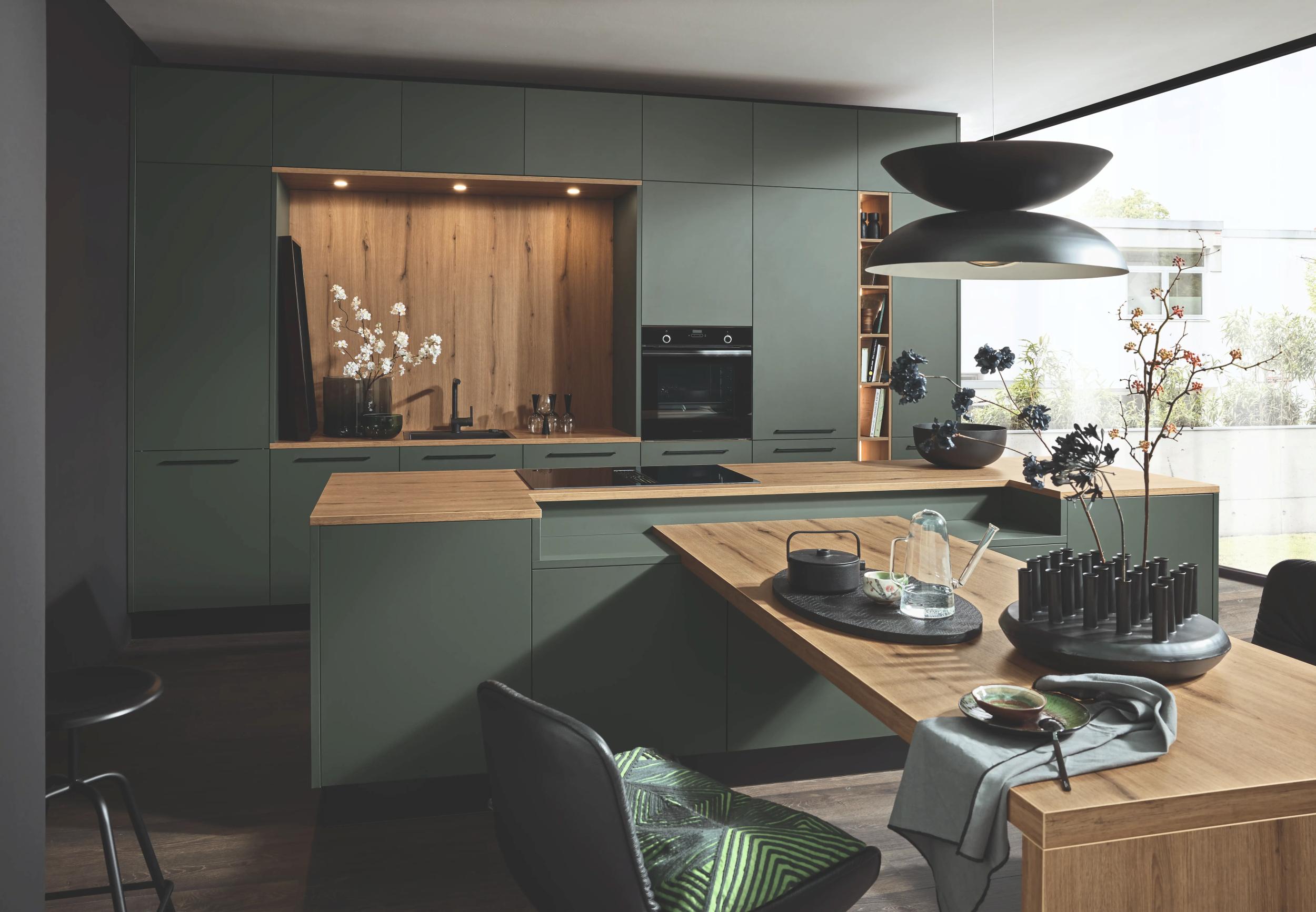 Moderne Nolte Küche in Black Green – minimalistische Eleganz trifft auf funktionale Perfektion. Die matten Fronten der Manhattan UNI Serie in Kombination mit natürlichen Materialien wie Vulkaneiche und integrierter Beleuchtung schaffen ein stilvolles und zeitloses Design. Ideal für moderne Küchen, die sowohl Ästhetik als auch höchste Funktionalität bieten.