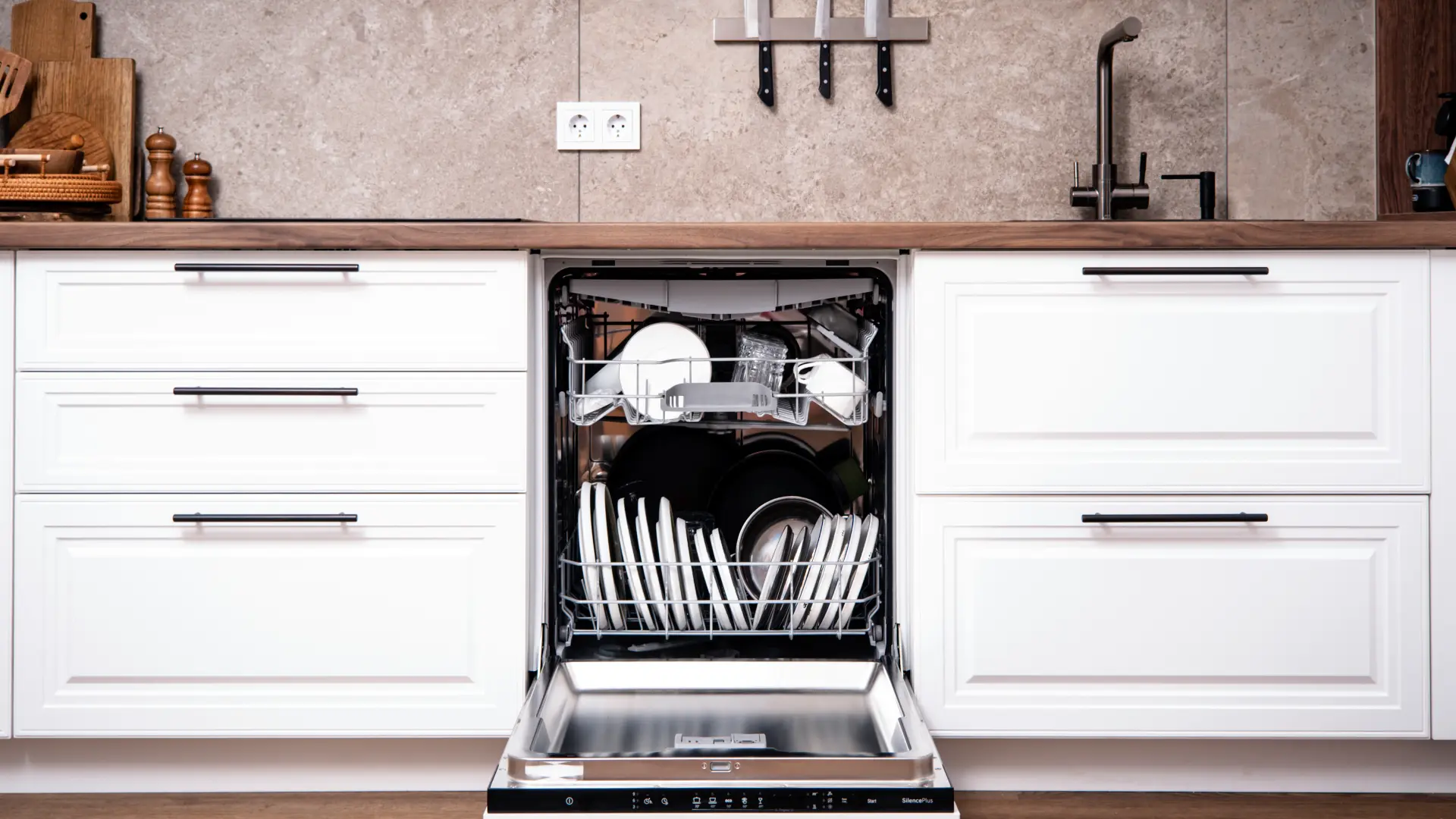 Geöffneter, teilbeladener Geschirrspüler mit einem Topf und Geschirr in einer weißen Küche.