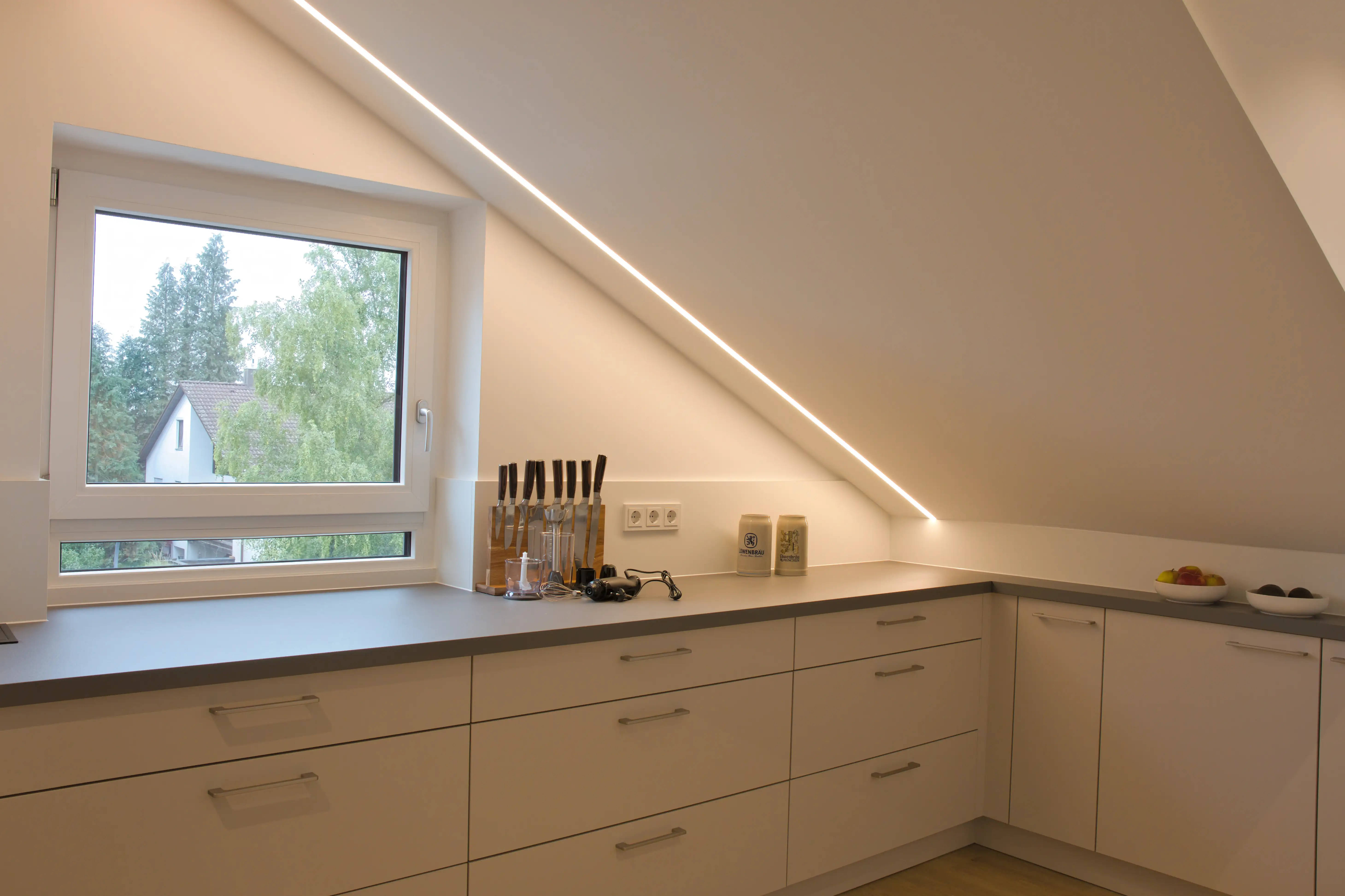 Pflegeleichte und robuste Laminat Arbeitsplatte passgenau in Dachschräge integriert. Moderne Küche vom Thoki Küchenstudio Wörthsee.