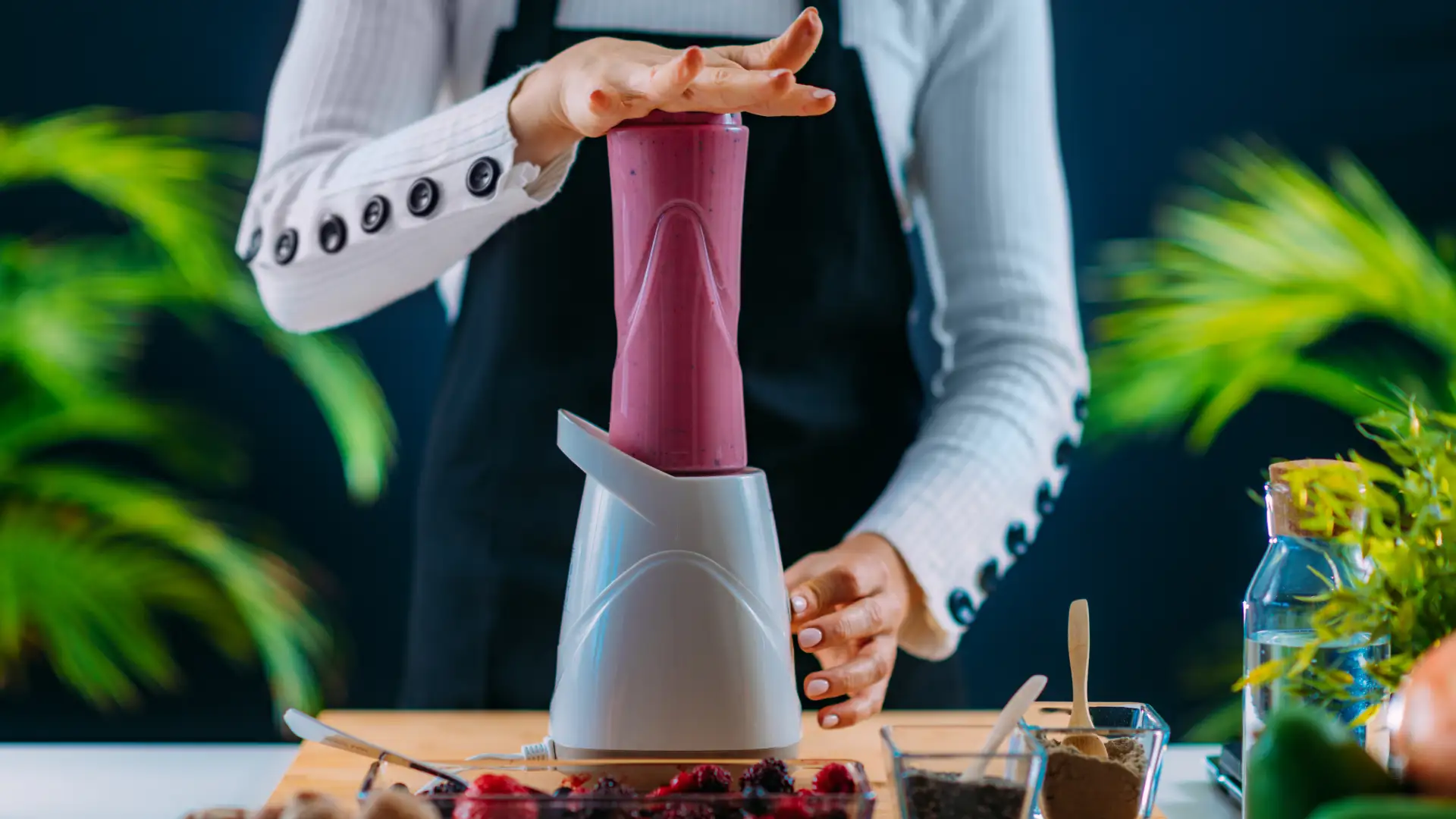 Person mixt frischen Beeren-Smoothie in einem elektrischen Standmixer in der Küche