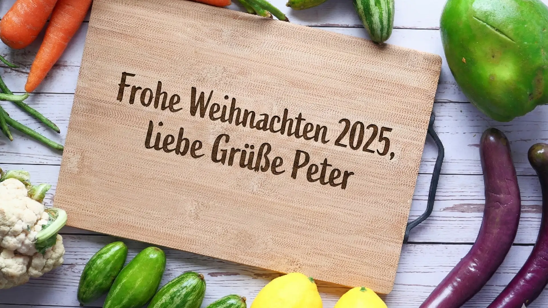 Graviertes Holzschneidebrett mit Weihnachtswunsch 2025 umgeben von frischem Gemüse
