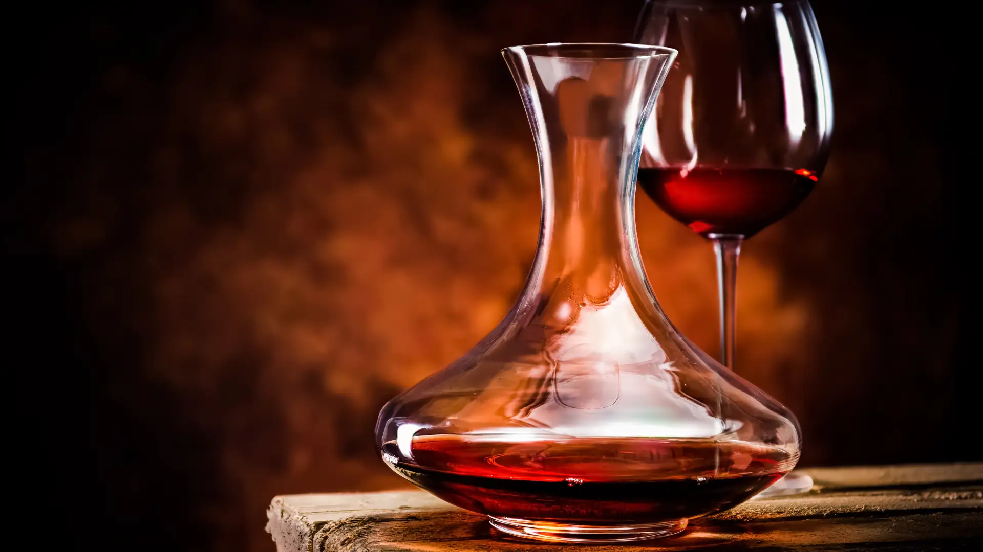 Ein Weindekanter aus Glas neben einem Viertel Rotwein