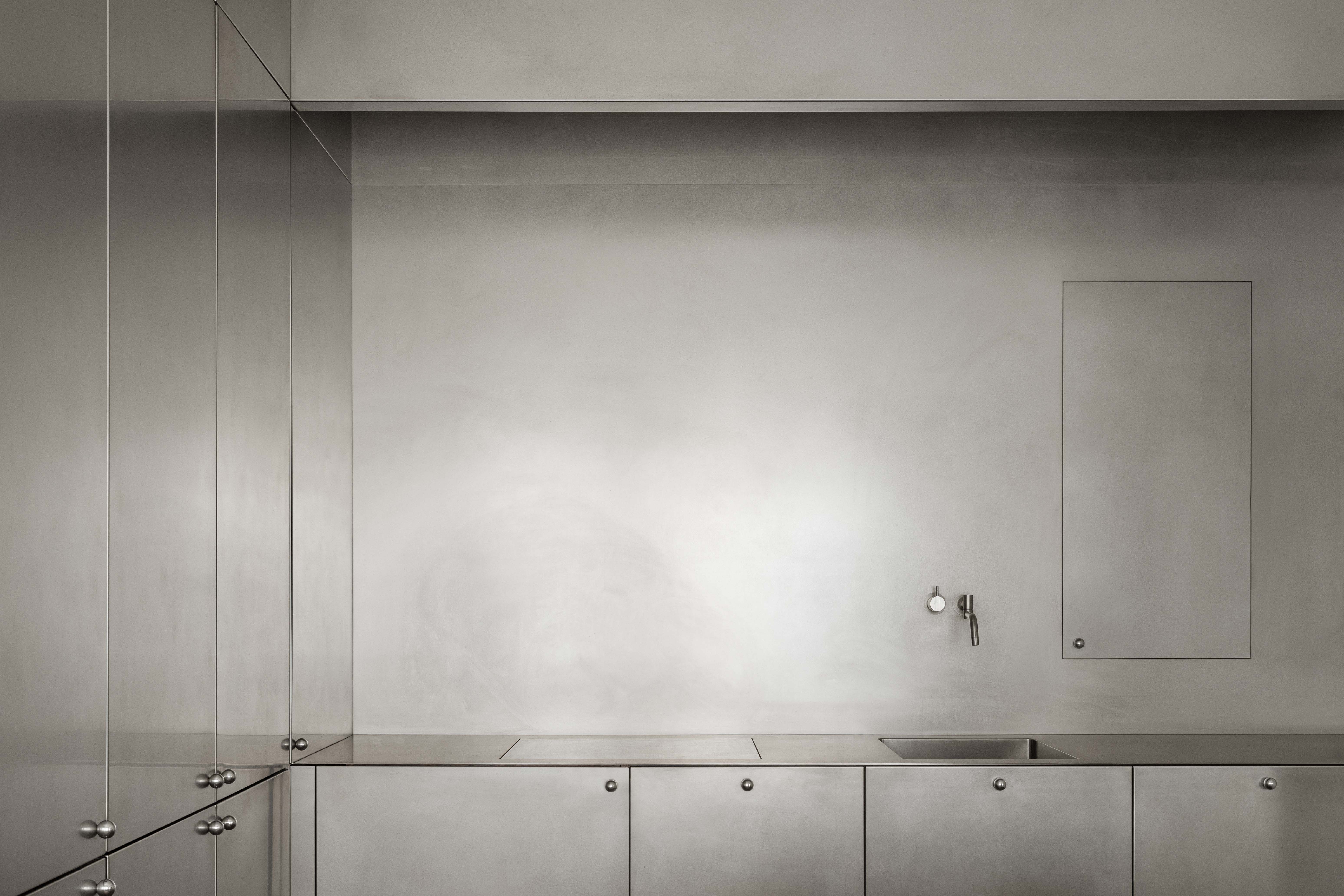 Kitchen in hand brushed stainless steel with warm toned wood seating featured in TG5 residential project in Stockholm, Sweden designed by Studio Daniel Kutlesovski