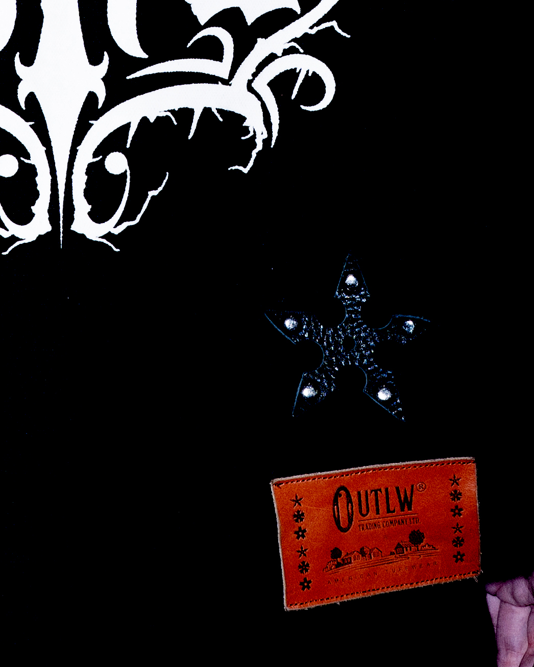 close up detail of black workwear jacket with leather patch embossed with 'OUTLW'