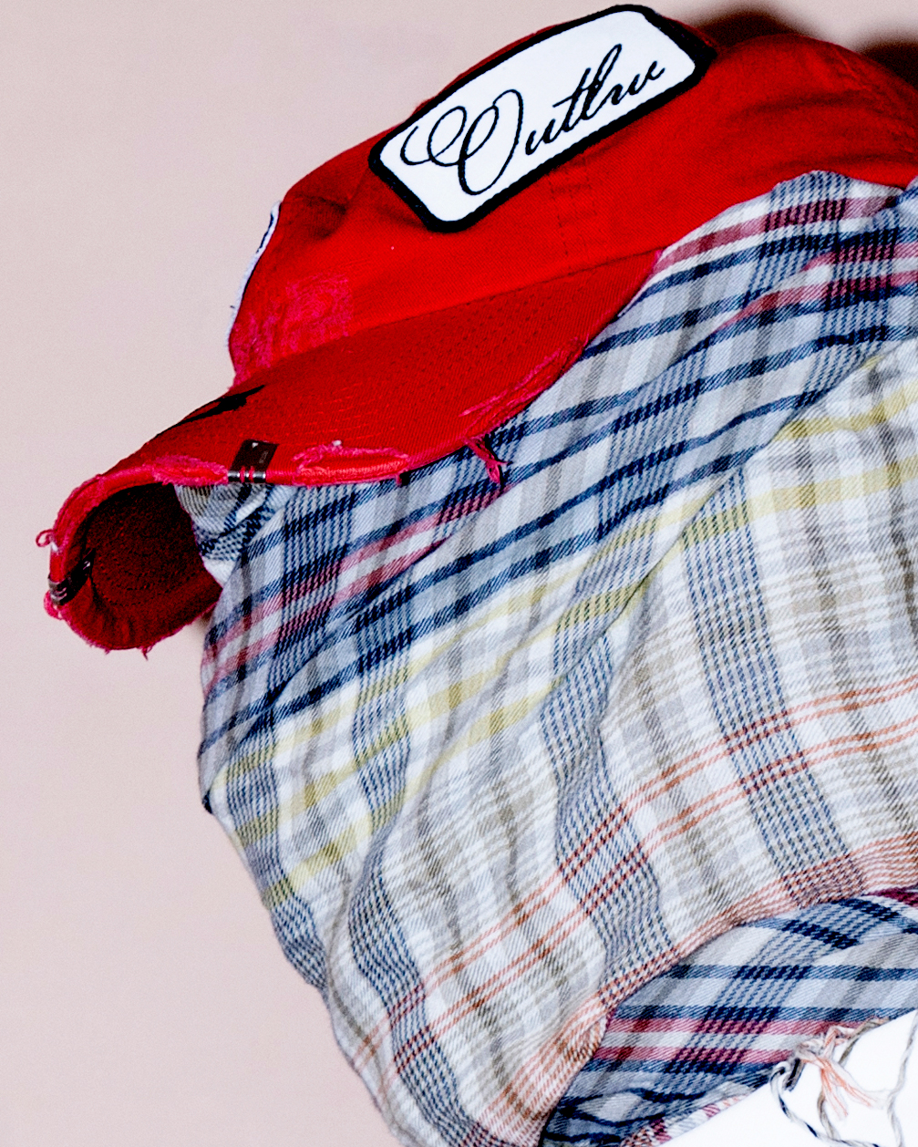 model wearing distressed red streetwear hat with patches and scarf covering face