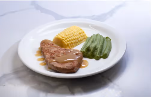 Oxa Care in-house chefs dining option of steak, pea puree and corn plated