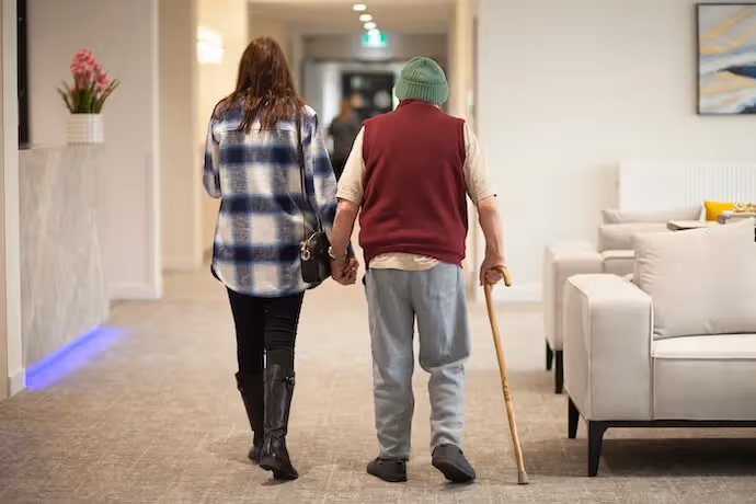 A daughter holding her elderly father's hand
