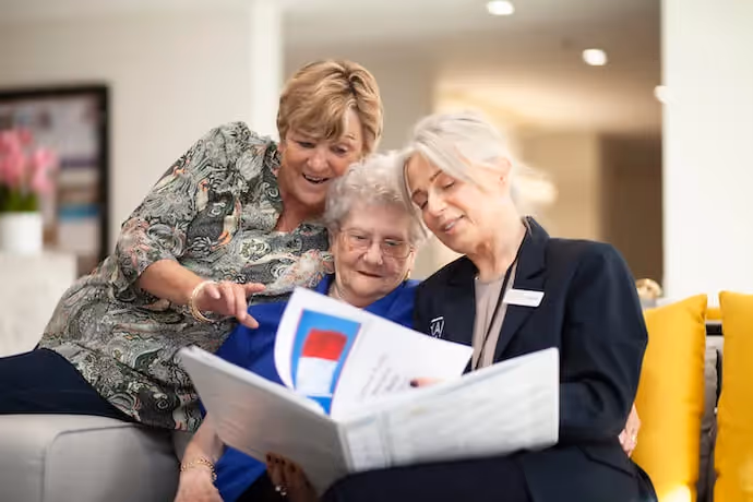 Elderly lady and her daughter going through a folder with an Oxa Care employee