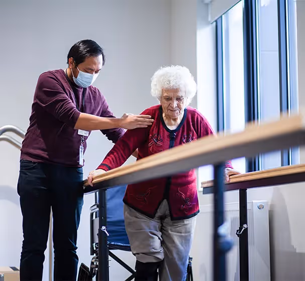 Elderly resident at South Morang aged care facility receiving mobility support from professional carer.