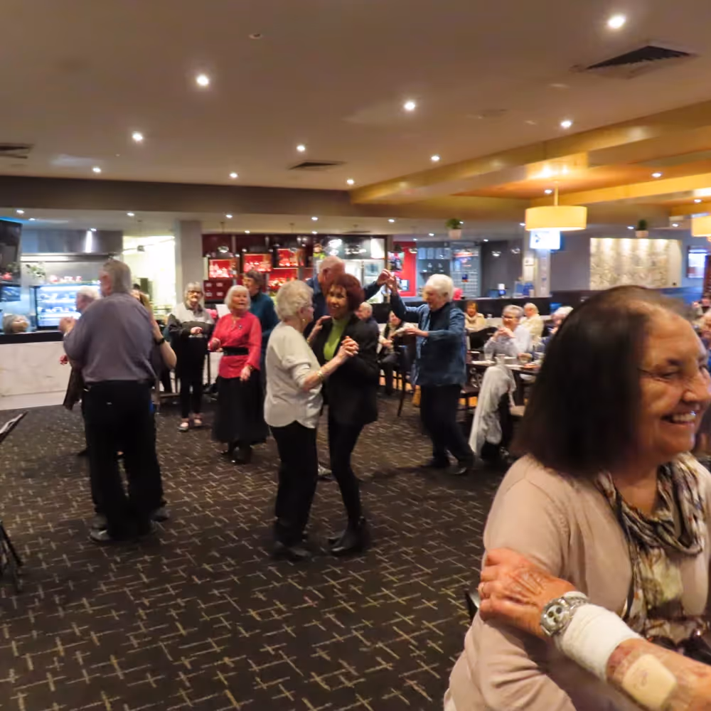 Seniors from Plenty enjoying a lively group dance at a local venue.