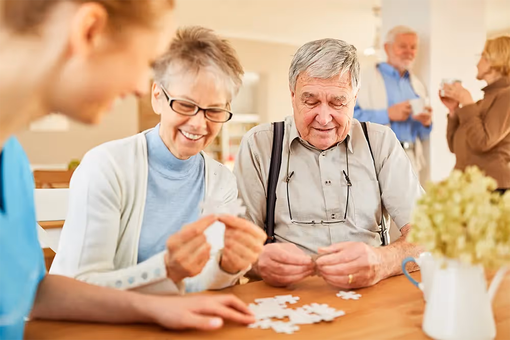 A group of seniors with Alzheimer’s Disease playing puzzles to exercise their minds and collaborate with others.