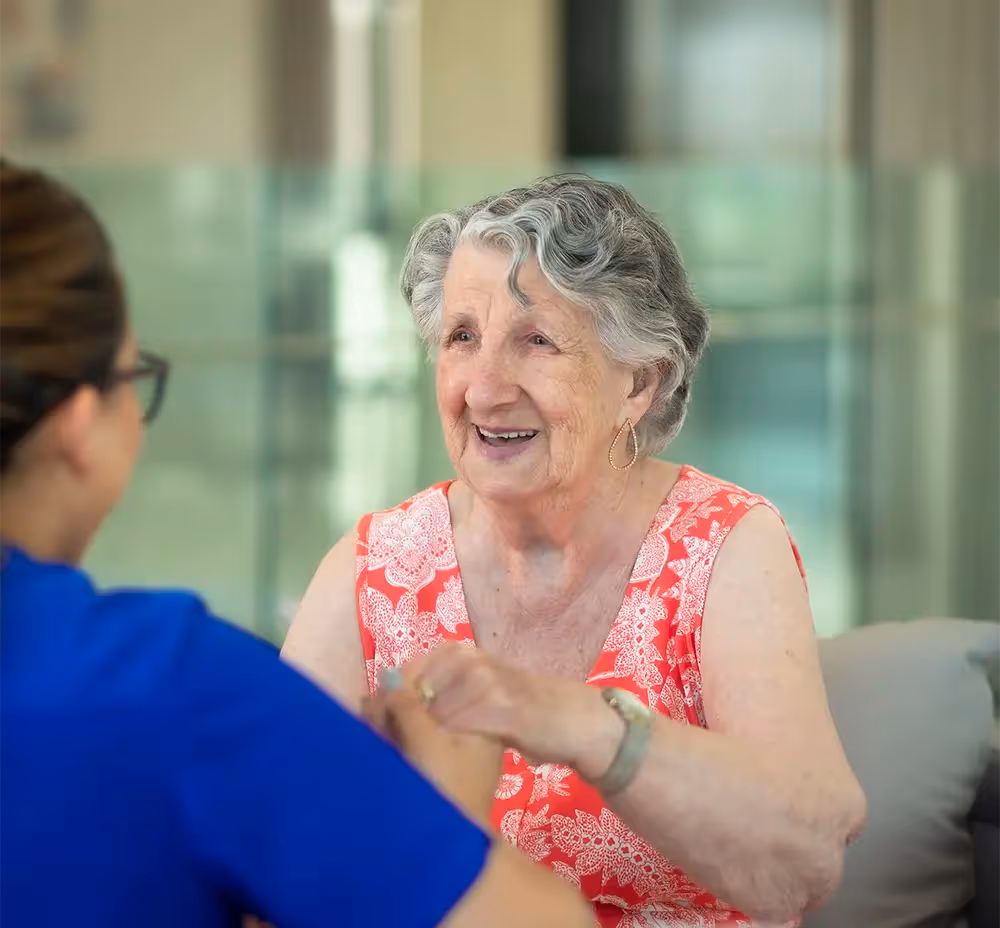 An older woman smiling warmly with her nurse, reflecting trust, compassion, and dedicated care in a supportive environment.
