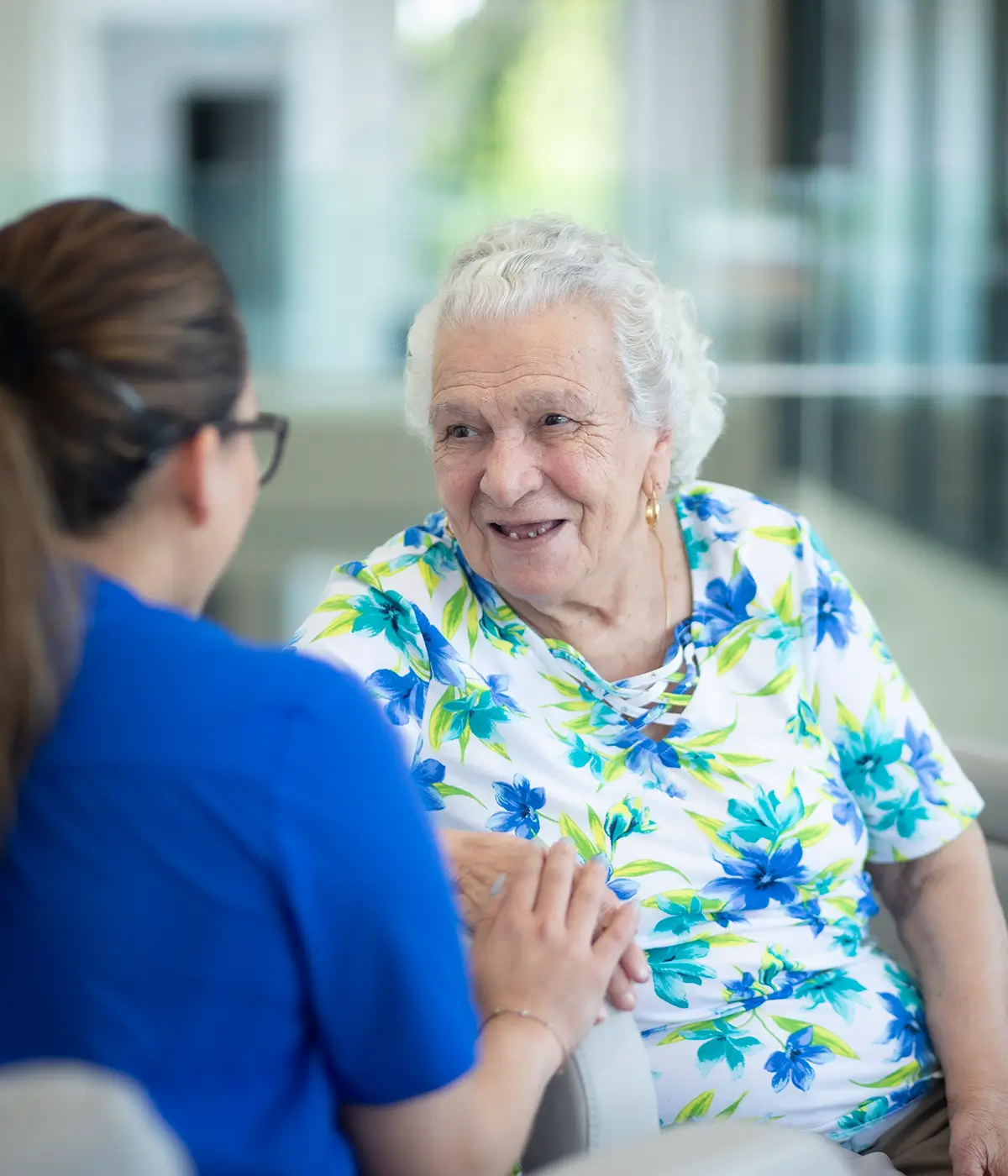 Smiling Italian elderly woman holding hands with a caregiver at Oxa Care