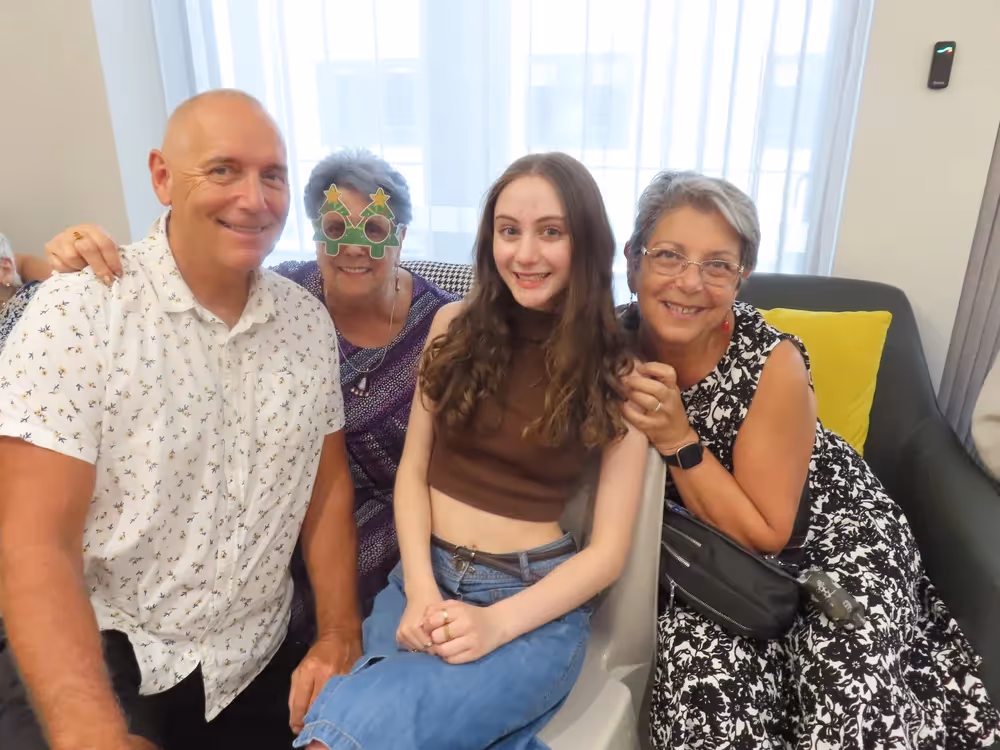 A cheerful family group poses together indoors.