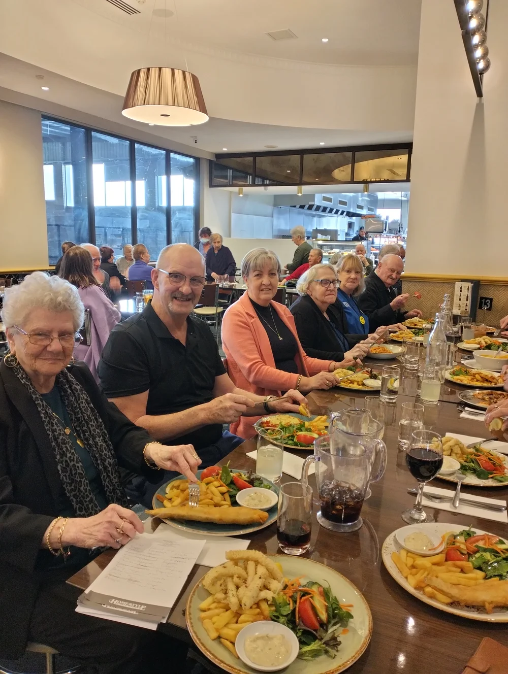 Large group of elderly friends dining together at a restaurant.