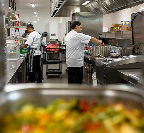 Chefs preparing fresh meals in a commercial kitchen at Oxa Care