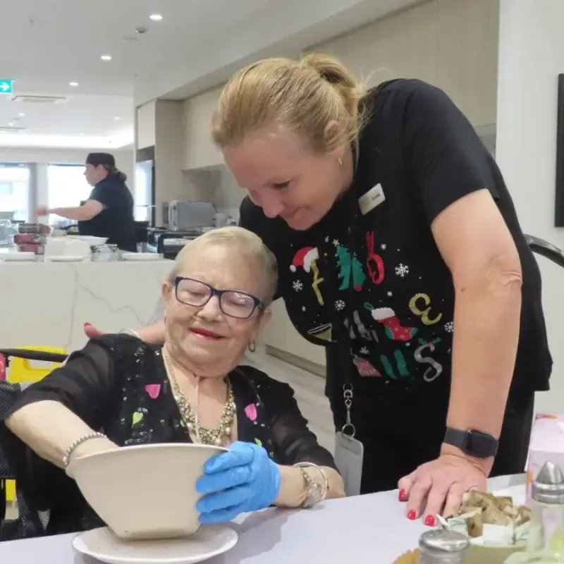 Care team member supporting resident during a cooking activity at Oxa Care.