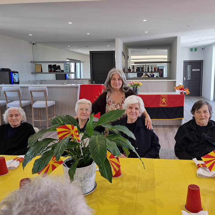 Residents and staff gathered together during a cultural celebration with Macedonian flags.