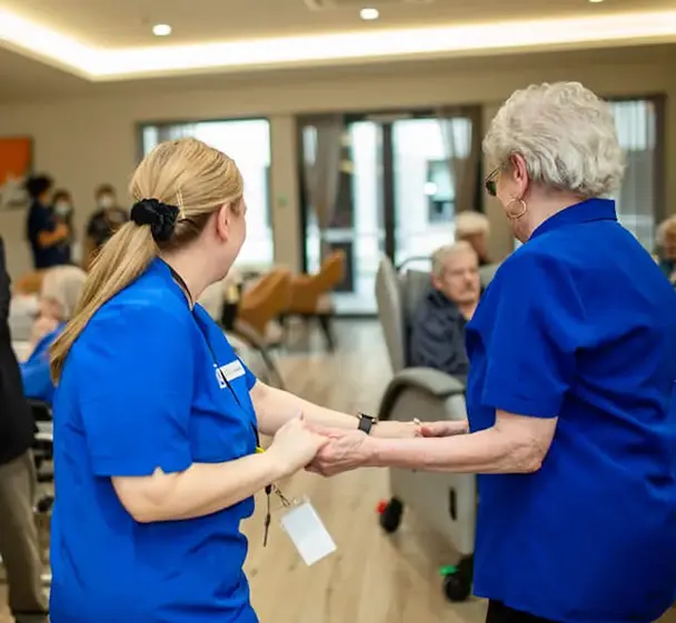 Care staff supporting resident during a lifestyle activity session in aged care home.