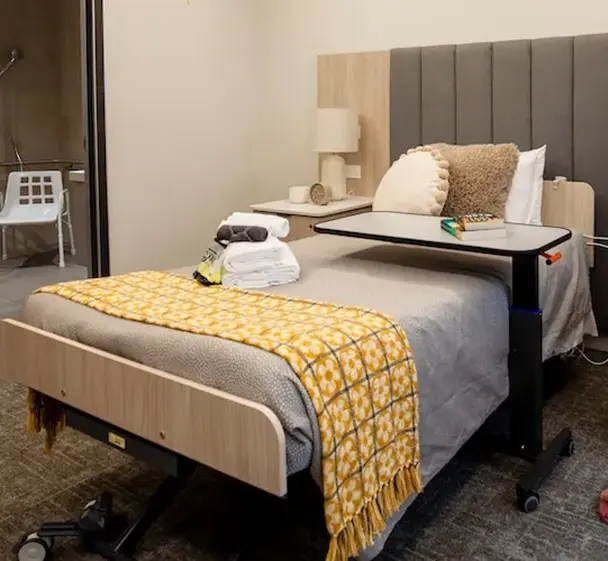 Private aged care room with electric bed, comfortable seating and accessible ensuite bathroom.