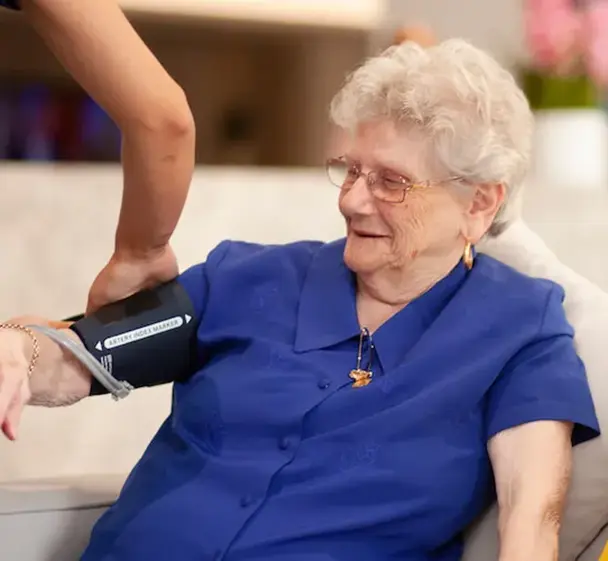 Nurse monitoring resident’s blood pressure in aged care home.