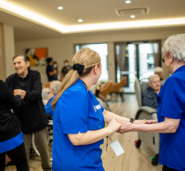 Care staff supporting residents during a social activity inside the aged care community.