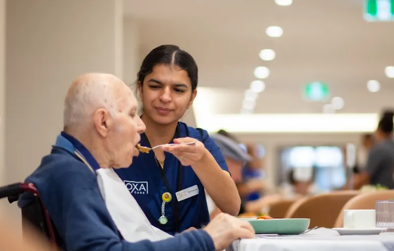 Nursing staff providing compassionate mealtime support to a resident.