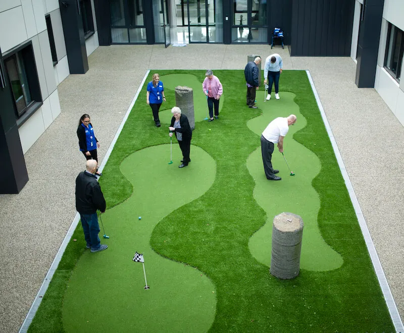 Residents enjoying outdoor leisure activities in landscaped courtyard.