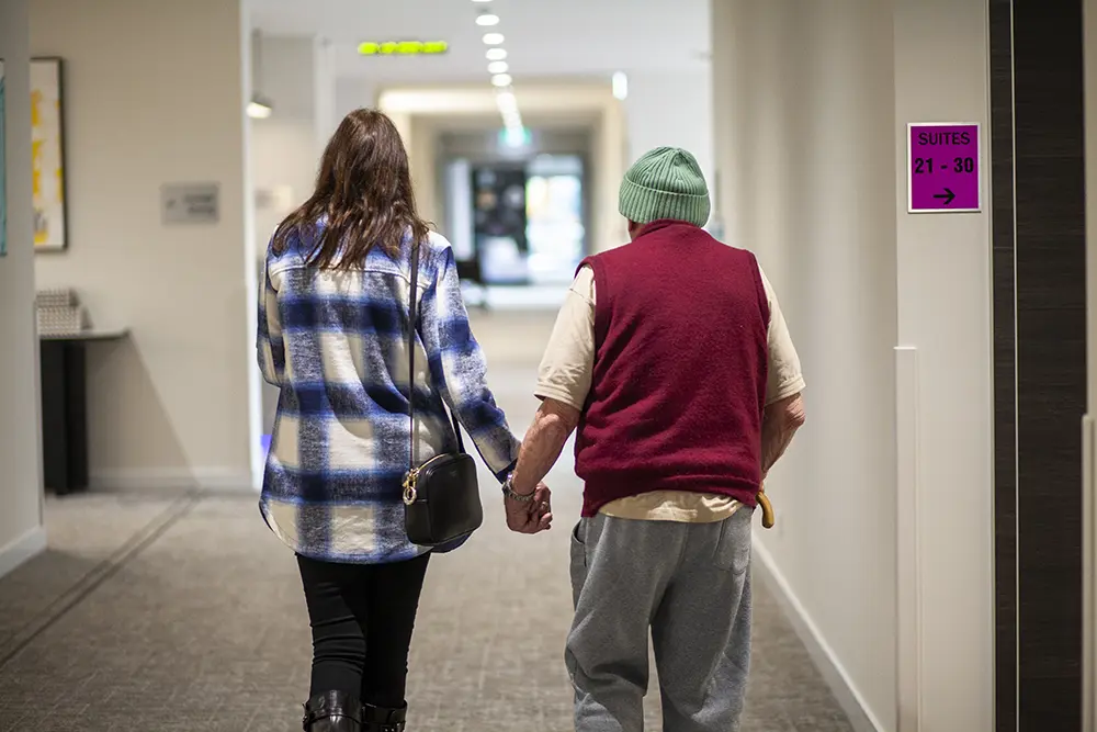 Care team member supporting a resident during a walk, encouraging independence and confidence with age.