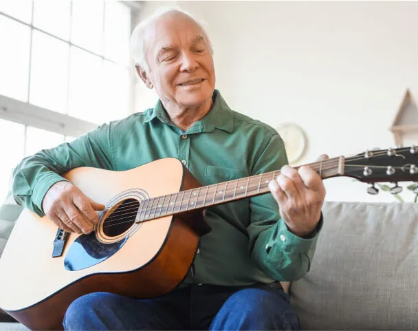 Resident playing guitar in a comfortable living space.