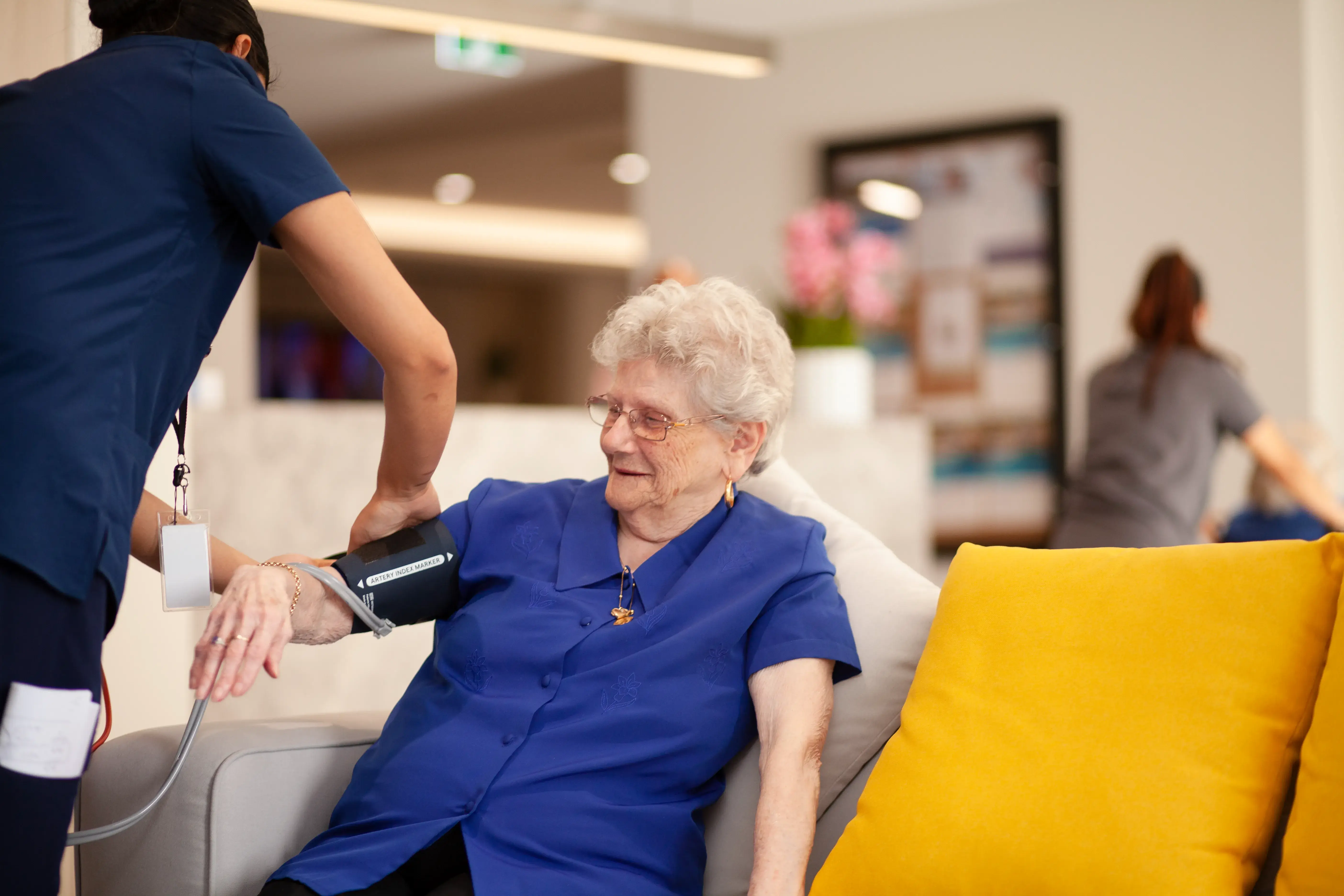 Nurse checking a resident’s blood pressure in a relaxed setting.