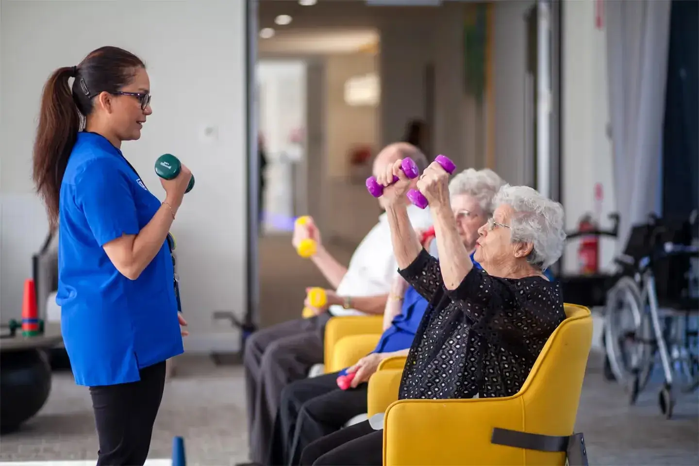 Residents participating in a guided seated exercise session with a staff member.