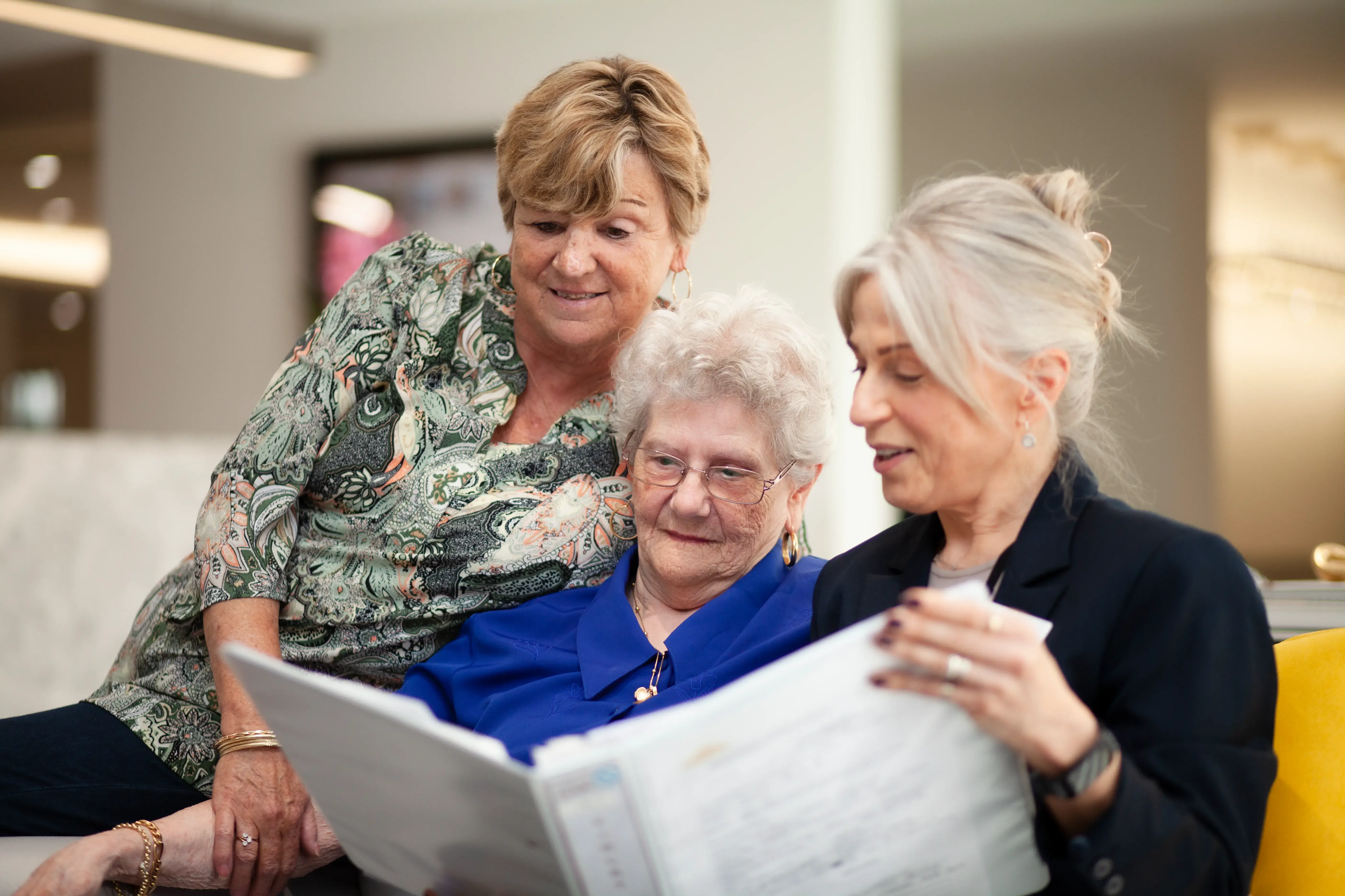 Family members reviewing documents together with a resident in a lounge area.