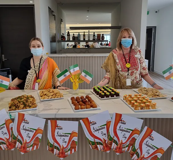 Two team members standing behind a display of homemade dishes prepared for a cultural celebration day.