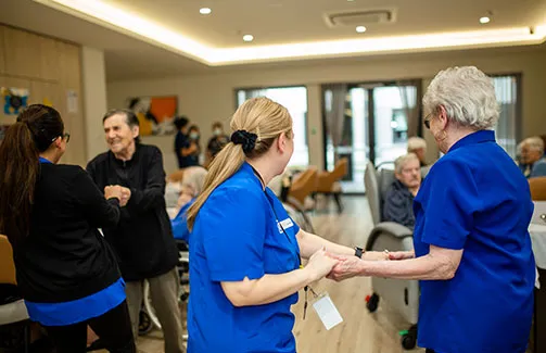Oxa Care staff and residents enjoy a lively social dancing session in a bright, spacious community room.