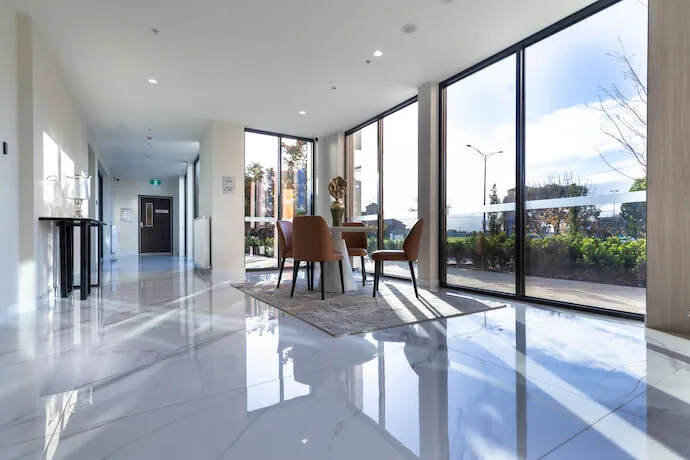 A modern Oxa Care lounge featuring marble floors, designer furniture, and large windows with scenic outdoor views.