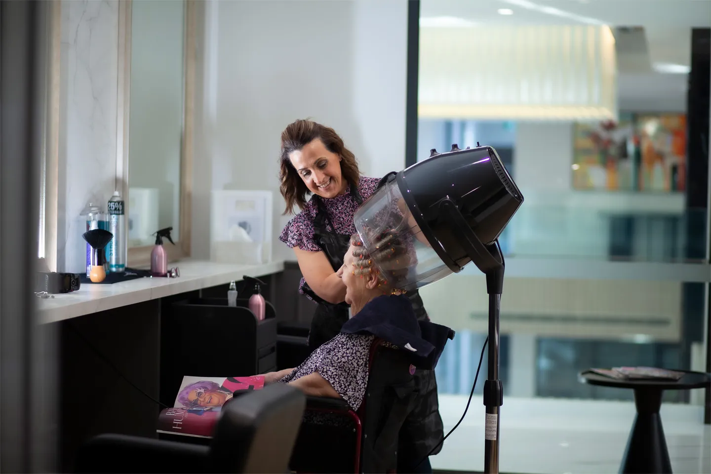 A resident enjoys a styling session with a professional hairdresser in the modern Oxa Care hair and beauty salon.