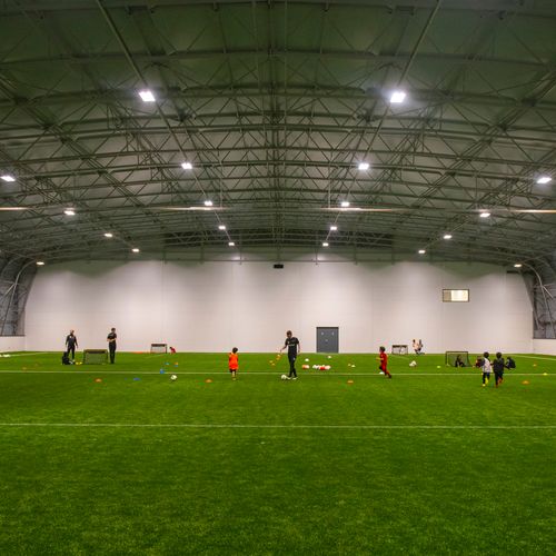Large indoor football pitch with children playing football