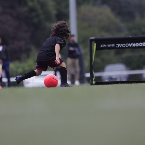 player dribbling with orange football about to score in a bazooka small sized goal