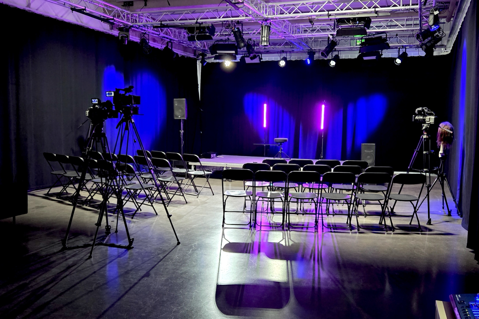 Iso studio tapahtumaa varten valmisteltuna: tuolirivit, lava, kamerat jalustoilla ja studiovalot.