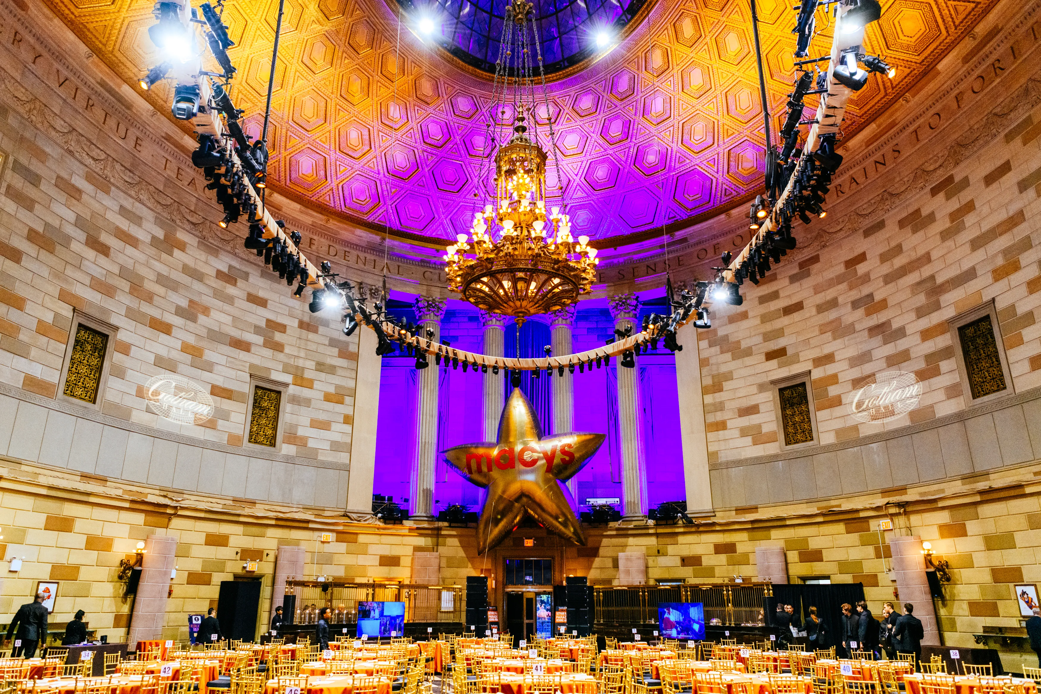Gotham Hall's domed ballroom with a gold chandelier and purple uplighting, set for the Thanksgiving Day Parade brunch