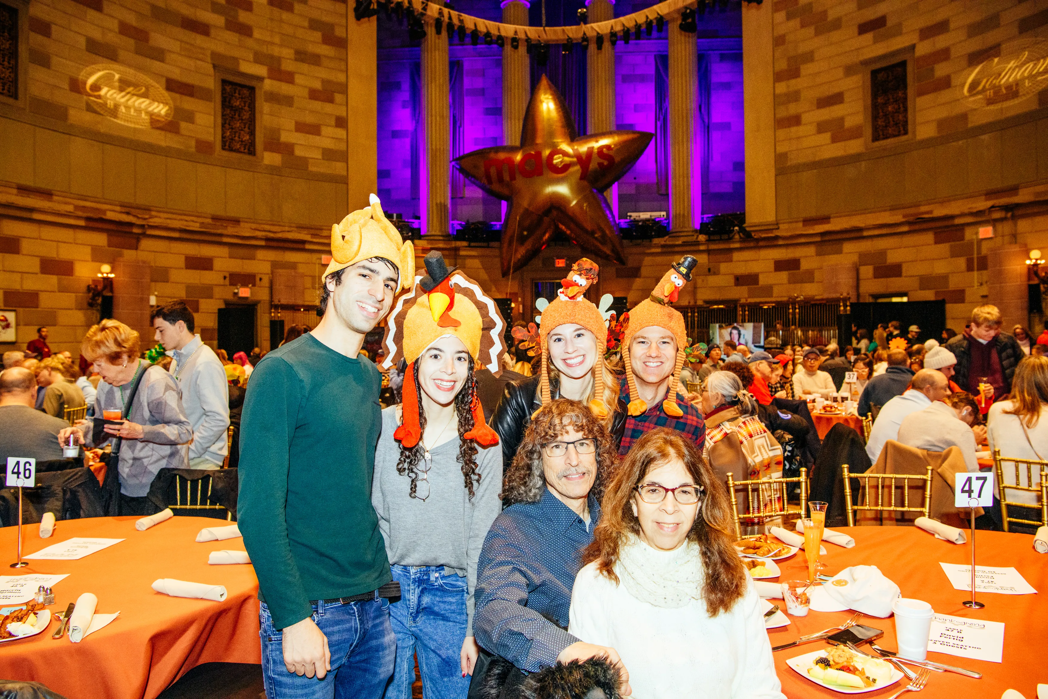 Guests in turkey hats at an orange-draped table during the Thanksgiving parade brunch at Gotham Hall