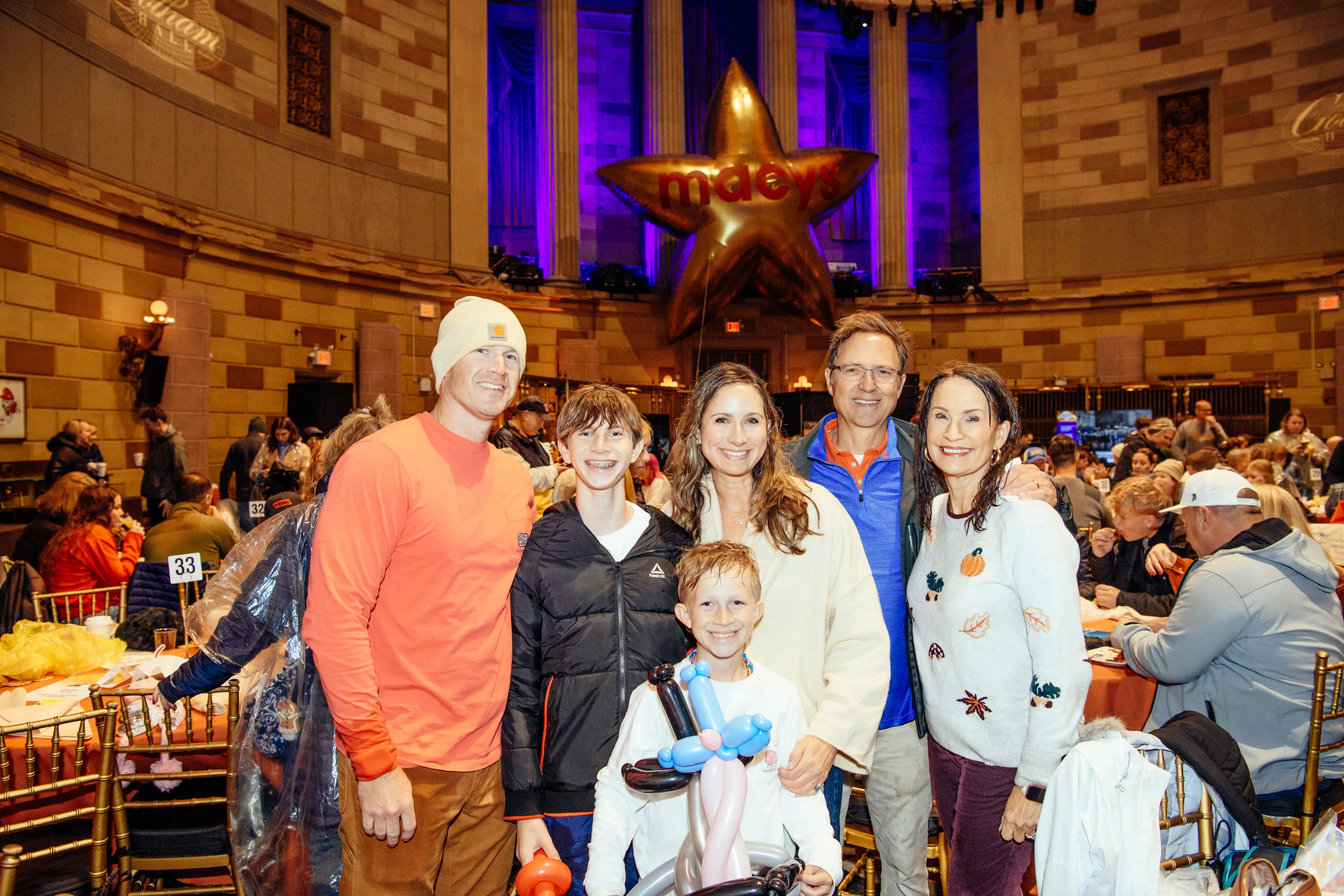 A family posing in the Gotham Hall ballroom, one child holding a balloon animal