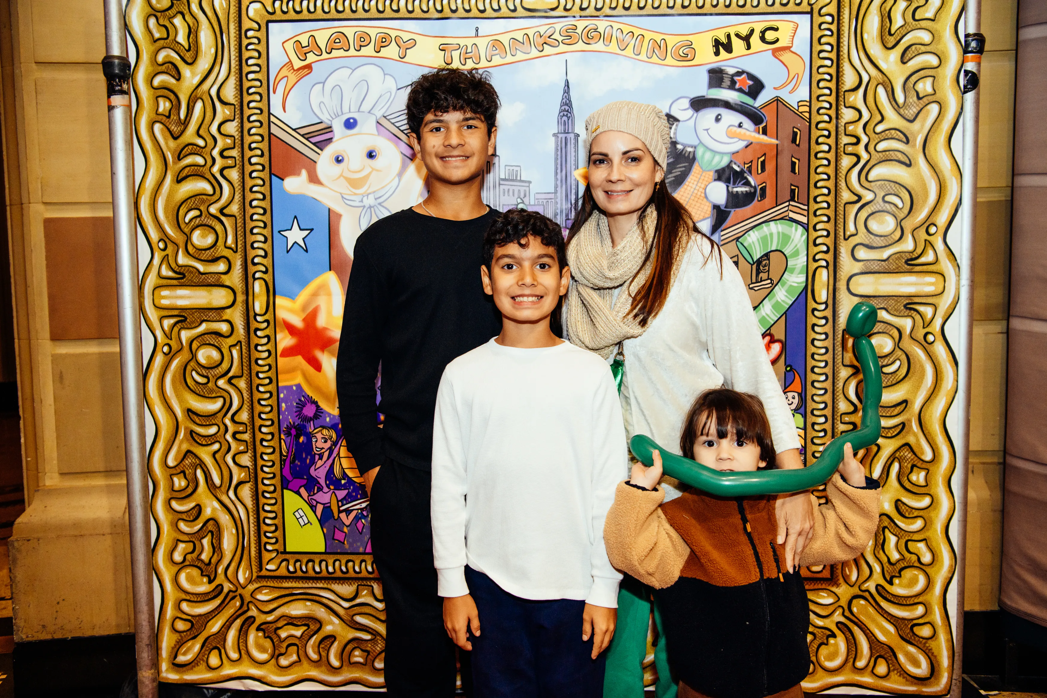 A mother and three kids, one holding a balloon animal, at the Happy Thanksgiving NYC photo backdrop