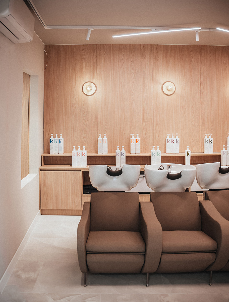 Wassalon in een kapsalon met bruine stoelen en wasbakken.