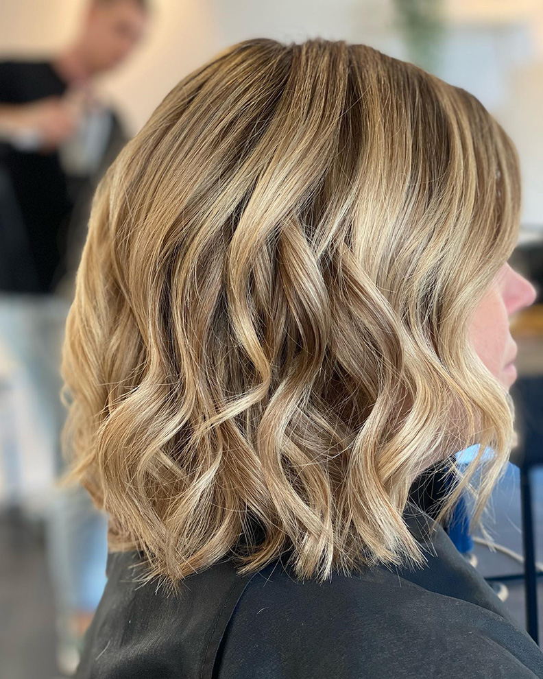 Blond halflang kapsel met zachte krullen.