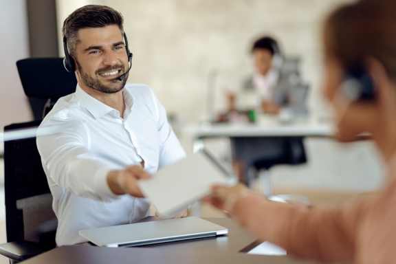 A person wearing a headset giving a piece of paper to a personAI-generated content may be incorrect.