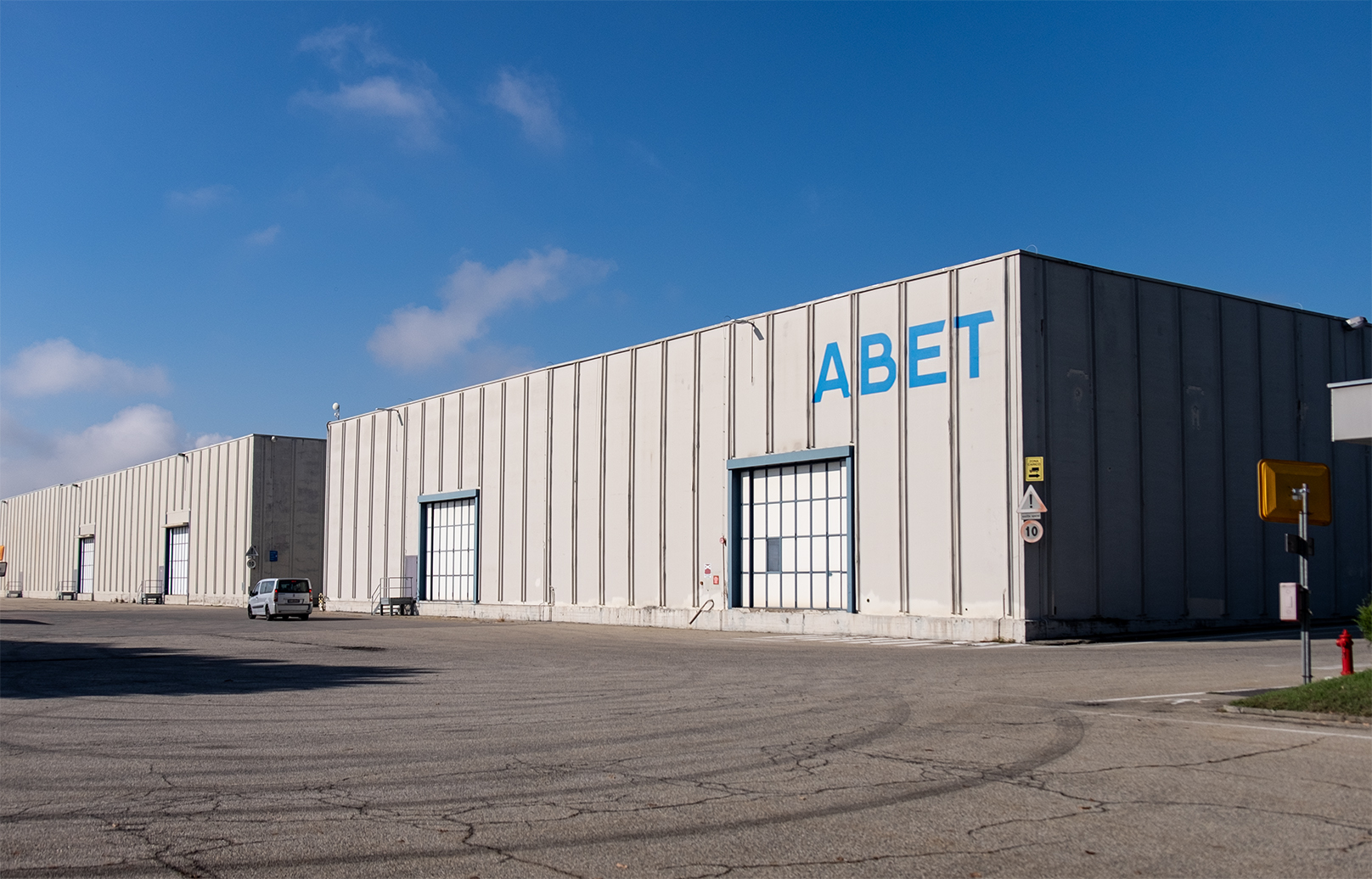 A factory with Abet written on it  and  a blue sky