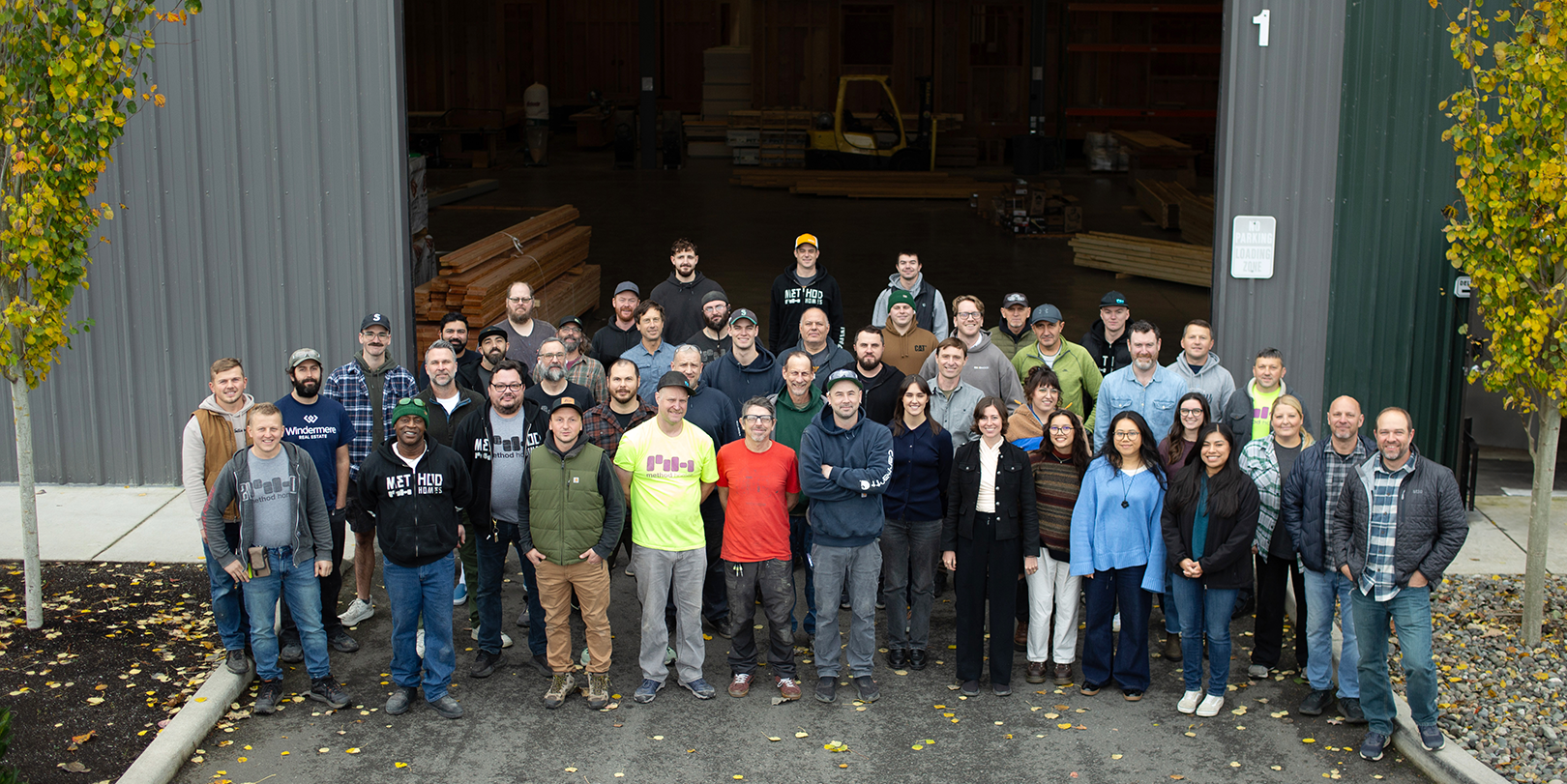 Large group of Method Homes employees standing outside the factory entrance, smiling at the camera.