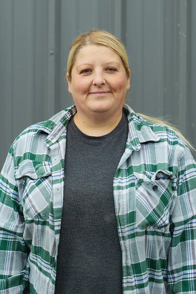 Smiling man with glasses, a beard, and long hair wearing a black Method Homes cap and a green plaid shirt.